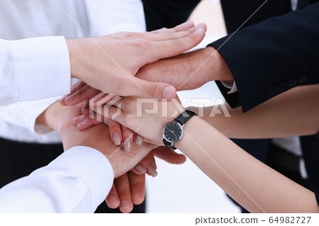 Group of people in suits crossed hands in pile Group of people in suits crossed hands in pile 64982727