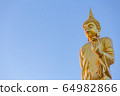 The standing buddha statue on blue sky, located in Chanthaburi, Thailand. 64982866