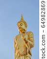 The standing buddha statue on blue sky, located in Chanthaburi, Thailand. 64982869