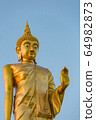 The standing buddha statue on blue sky, located in Chanthaburi, Thailand. 64982873