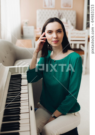 Cheerful lady sits on the chair near the white 64983153