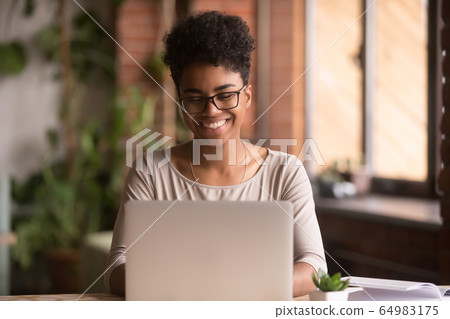 Happy mixed race woman student using laptop working studying indoor 64983175