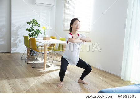 A woman exercising in the living room 64983593