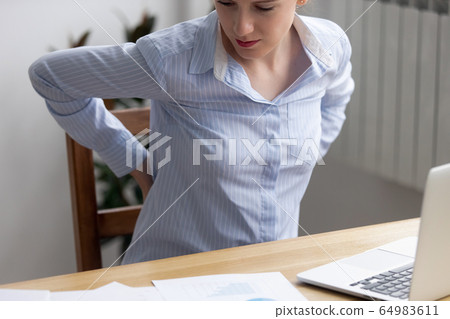 Backpain in office concept, tired fatigued business woman rubbing back 64983611