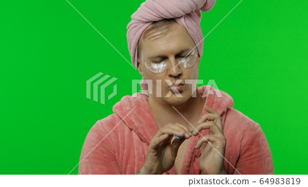 Transsexual man in bathrobe with eye patches making manicure. Chroma key Transsexual man in bathrobe with eye patches making manicure. Chroma key 64983819