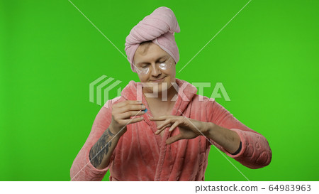 Portrait of transsexual man in bathrobe spraying perfume on neck and wrist Portrait of transsexual man in bathrobe spraying perfume on neck and wrist 64983963