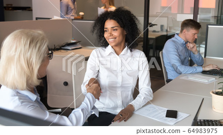 Smiling young african employee client handshake old business manager mentor Smiling young african employee client handshake old business manager mentor 64983975