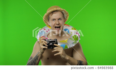 Shirtless man tourist photographer is taking photos on retro camera. Chroma key 64983988