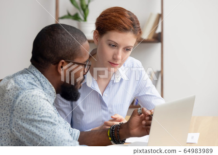 African mentor consultant explaining computer work to caucasian intern client 64983989