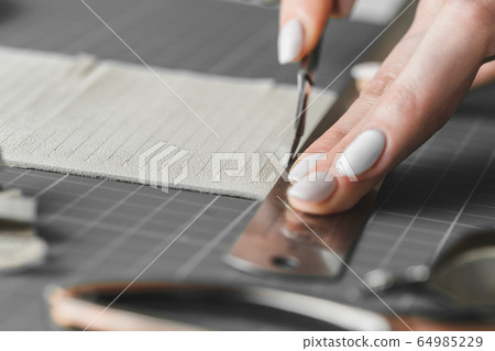 Woman cutting leather fringe for handbag details 64985229