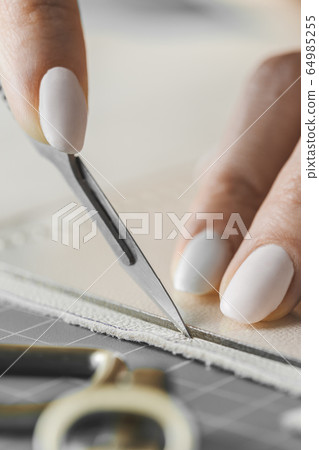 Woman measuring and cutting leather in a workshop Woman measuring and cutting leather in a workshop 64985255