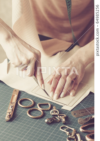 Woman measuring and cutting leather in a workshop Woman measuring and cutting leather in a workshop 64985256