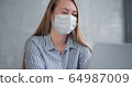 Young Caucasian doctor woman working from home online using laptop, consulting people on quarantine wearing face mask. 64987009