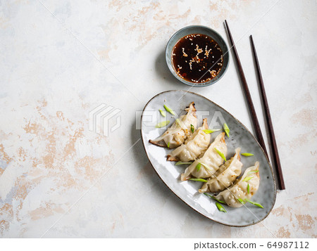 Chinese traditional dumplings - gyoza with pork and vegetables on an oval plate with soy sauce i 64987112