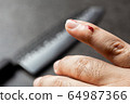 Bleeding finger by kitchen knife on black 64987366