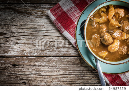 Meatballs in gravy with cast noodles. 64987859