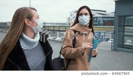 Social activism during coronavirus crisis. Two Caucasian female doctors walk on empty city street in medical face masks. Social activism during coronavirus crisis. Two Caucasian female doctors walk on empty city street in medical face masks. 64987905