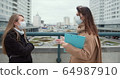 Epidemic control social care workers. Two young Caucasian female social care employees in face masks talk outside. 64987910