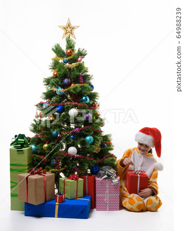 Girl unpacks a Christmas present at the Christmas Girl unpacks a Christmas present at the Christmas 64988239