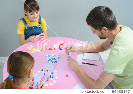 Family plays board games at the table, top view 64988377