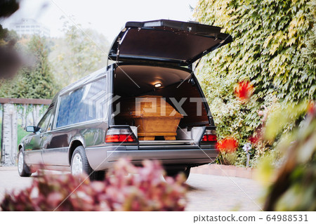a coffin in the back of a car at a funeral 64988531