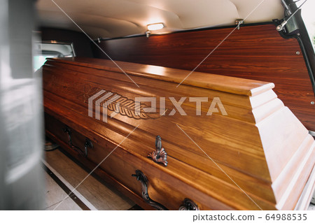 a coffin in the back of a car at a funeral 64988535