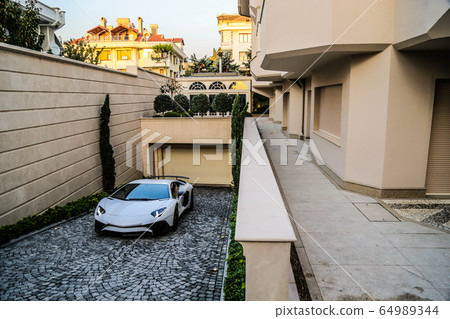 A silver sport car driving out of a garage of a building 64989344
