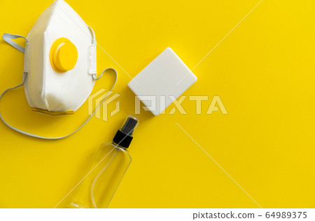 Protective mask, respirator ffp, soap and antiseptic lie on a yellow background. Anti-virus protection kit against covid-19. Coronavirus pandemic 2019. Protective mask, respirator ffp, soap and antiseptic lie on a yellow background. Anti-virus protection kit against covid-19. Coronavirus pandemic 2019. 64989375