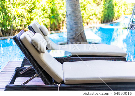 Empty chair deck lounge around swimming pool in hotel resort 64993016