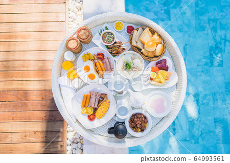 Floating breakfast set in tray with fried egg omelette sausage ham bread fruit milk juice coffee Floating breakfast set in tray with fried egg omelette sausage ham bread fruit milk juice coffee 64993561