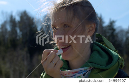 Woman applying moisturizing lipstick 64994607