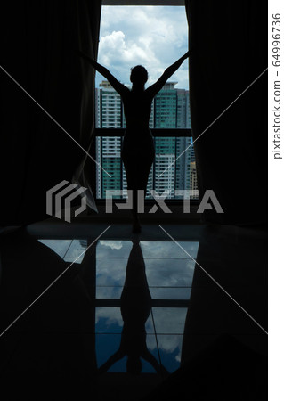 A slender girl is looking at the city through a A slender girl is looking at the city through a 64996736