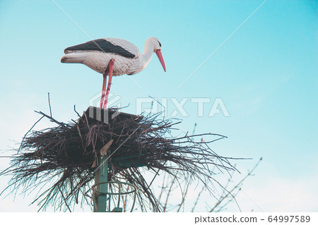 Stork in the nest, garden sculpture against the sky 64997589