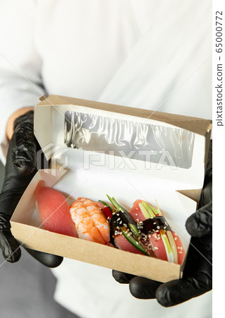 Beautiful sushi in craft packaging for delivery in the hands of a chef. Food delivery. Food at home. Delivery concept. Beautiful sushi in craft packaging for delivery in the hands of a chef. Food delivery. Food at home. Delivery concept. 65000772