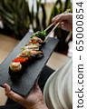 Assorted fresh sushi gunkan maki with seafood. set of gunkans in hands. Selective focus. 65000854