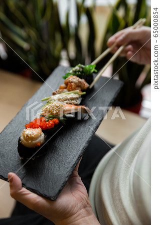 Assorted fresh sushi gunkan maki with seafood. set of gunkans in hands. Selective focus. Assorted fresh sushi gunkan maki with seafood. set of gunkans in hands. Selective focus. 65000854