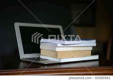 Books on top of computer laptop. Online education. 65000982