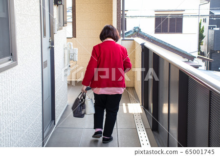 走在公寓共同的走廊裡的年長婦女 65001745
