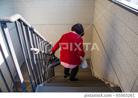 Elderly woman down the stairs with luggage 65003261