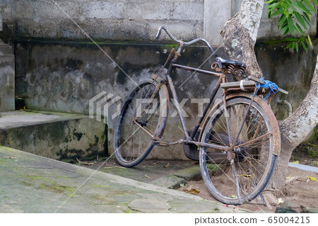 Parked old bicycle near stone wall in Asia. 65004215