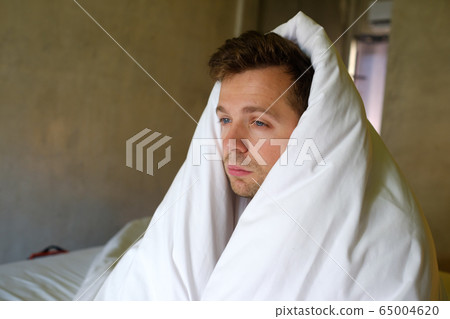 Sad caucasian man sitting on his bed with his head 65004620