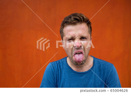 A young man with a grimace of disgust on his face. 65004626