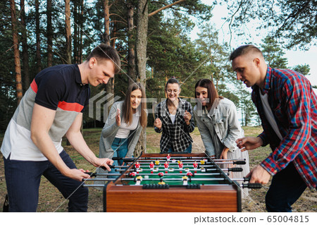 Friends play table football or kicker outdoors. Players and fans rejoice in the victory. Friends play table football or kicker outdoors. Players and fans rejoice in the victory. 65004815
