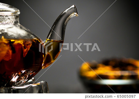 Horizontal photo of the tea set on a black background. Glass transparent teapot and cup. Black leaf tea. Horizontal photo of the tea set on a black background. Glass transparent teapot and cup. Black leaf tea. 65005097