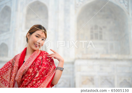 Asian woman wearing red saree indian traditional dress against Taj Mahal 65005130