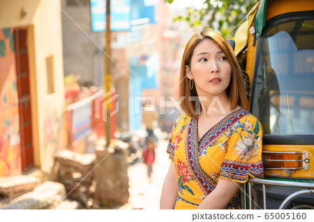 Portrait of young woman standing beside of Tuktuk local taxi in Jodphur India 65005160