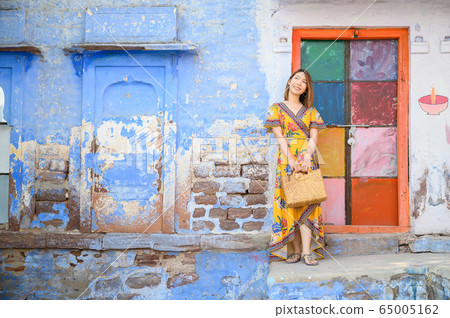 Portrait of young woman in front colorful building wall in Jodphur blue city in India 65005162