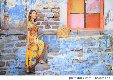 Portrait of young woman in front colorful building wall in Jodphur blue city in India 65005163
