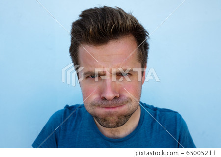 Humorous emotional portrait of grimacing young man Humorous emotional portrait of grimacing young man 65005211