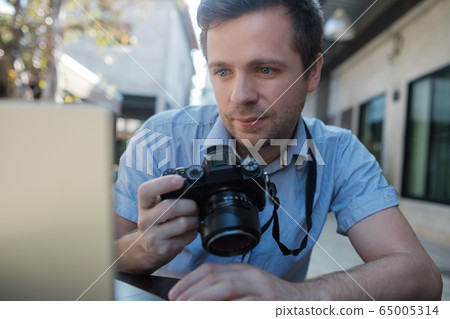 Caucasian young man photographer is editing photos 65005314